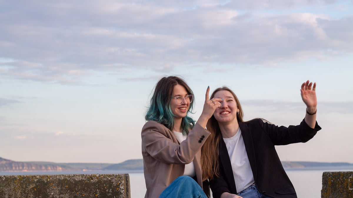 Two women laughing and pointing at the sky.