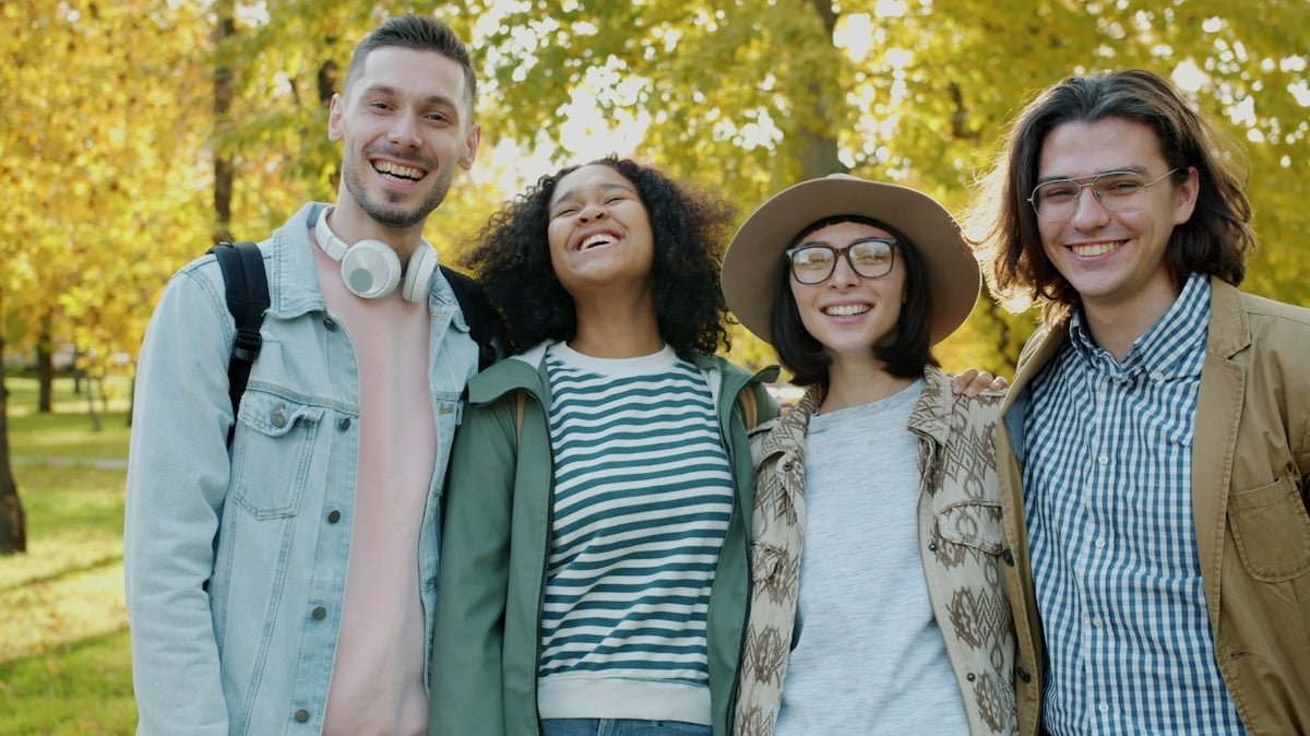 Four smiling friends posing together outdoors in autumn.