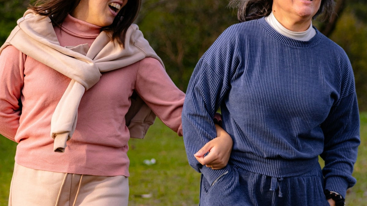 Two women laughing and walking in a park.