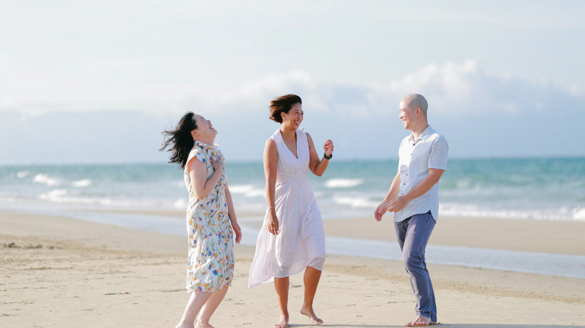 Three friends laughing on a sunny beach