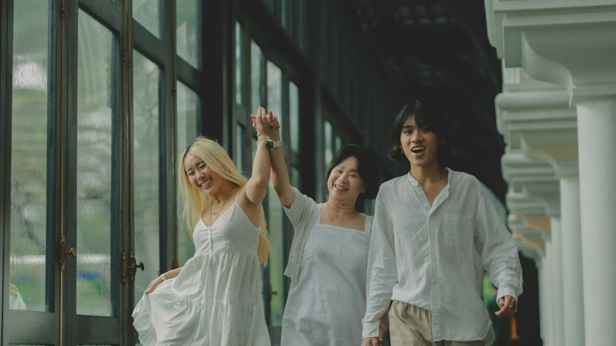 Three friends in white clothes walking together joyfully.
