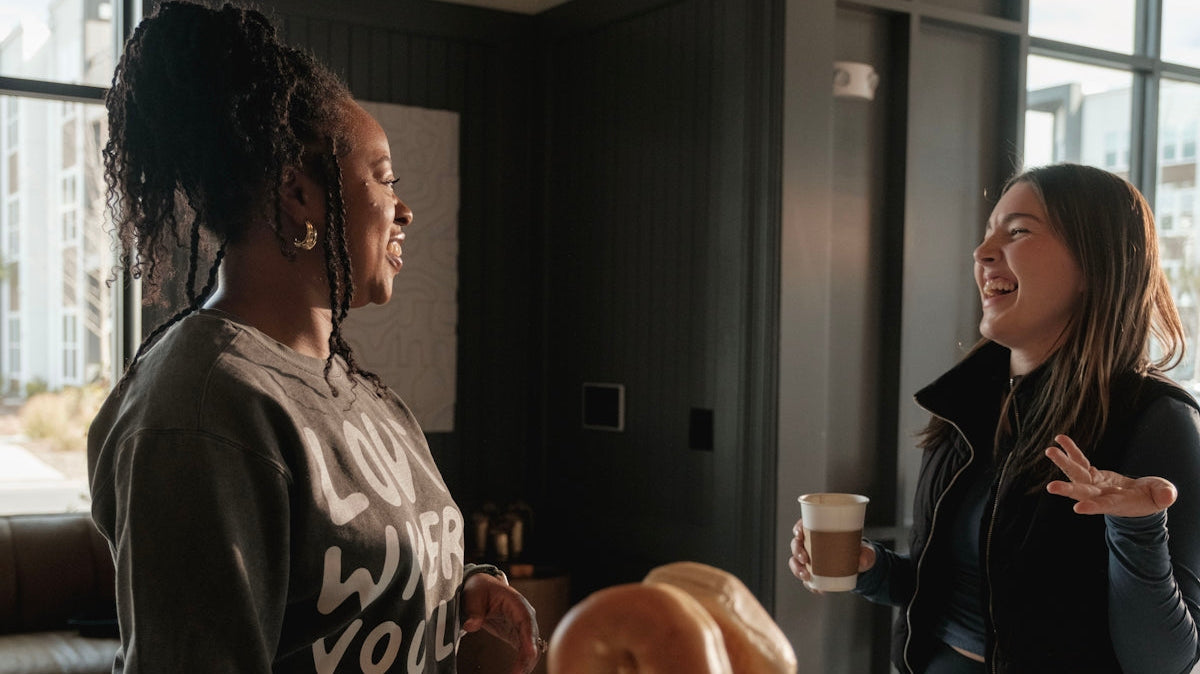 Two women talking and laughing indoors.