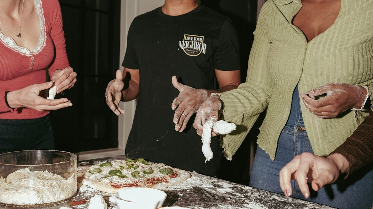 Friends making pizza together at a kitchen counter.