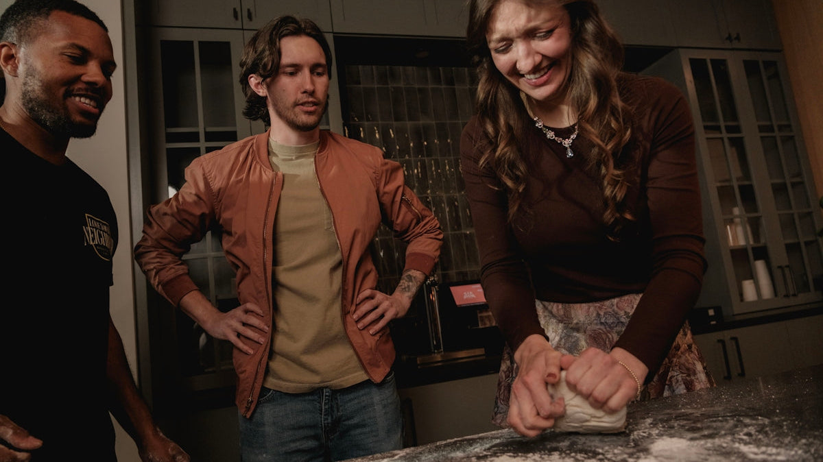 Three friends making dough together in a kitchen