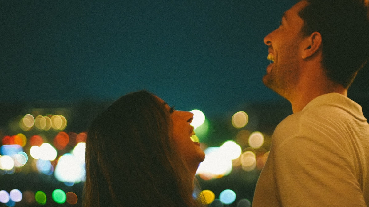 A couple laughing together at night with bokeh lights
