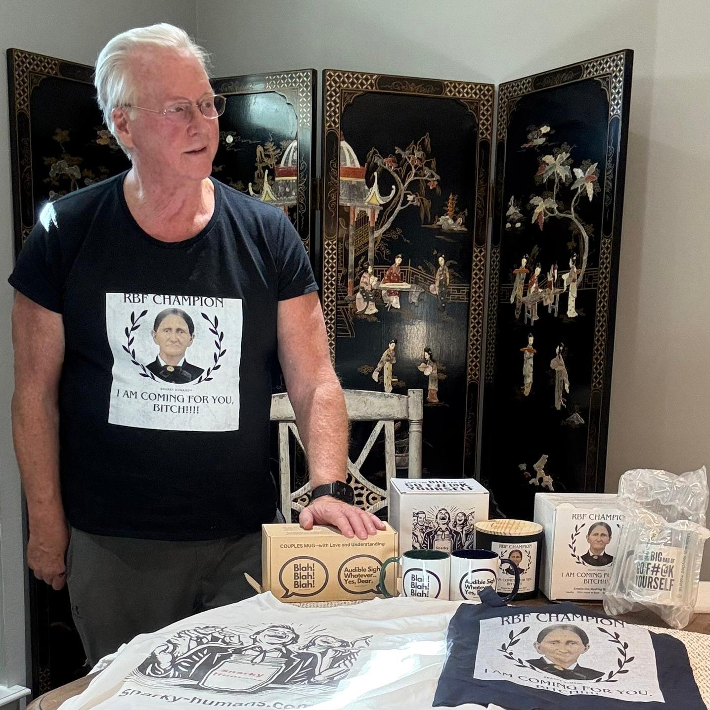 A man stands beside a table displaying humorous products