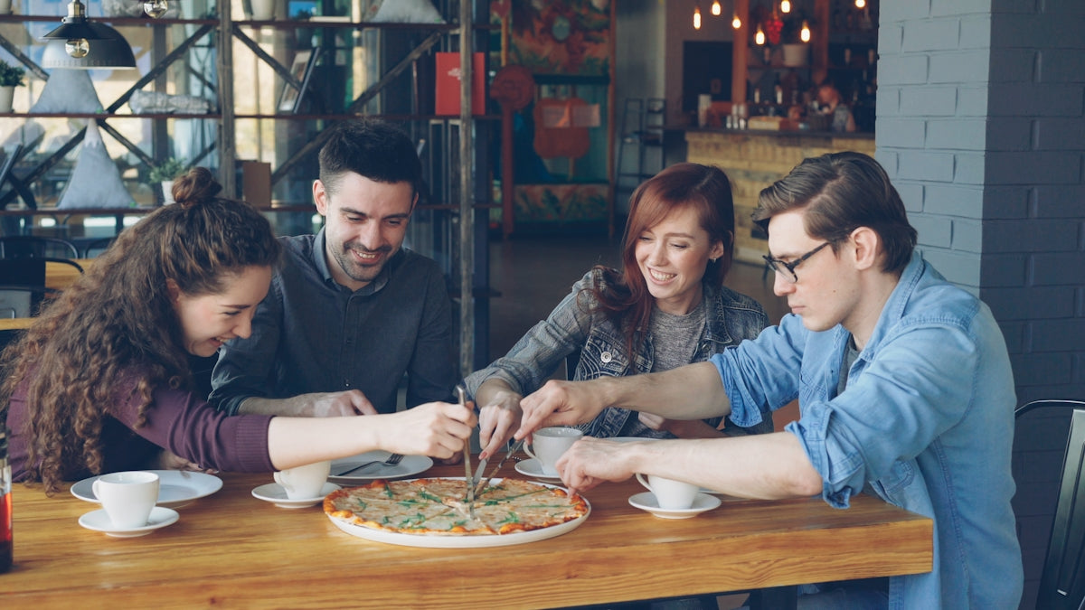 Friends share a pizza together at a restaurant.