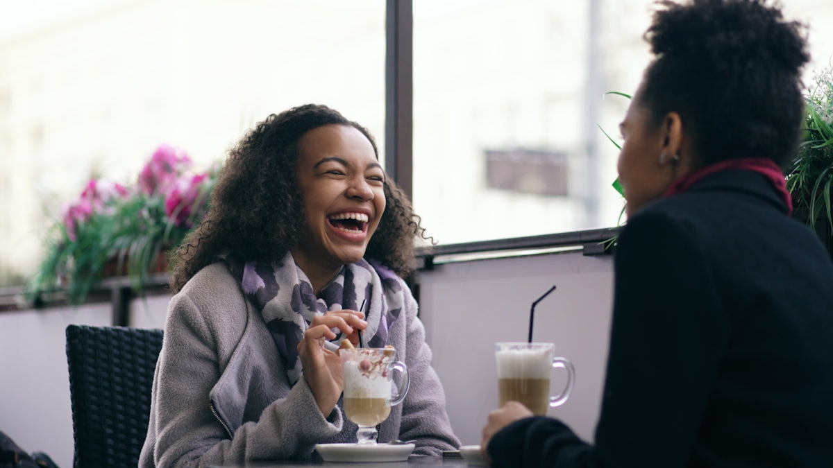 Two women laughing at a cafe table