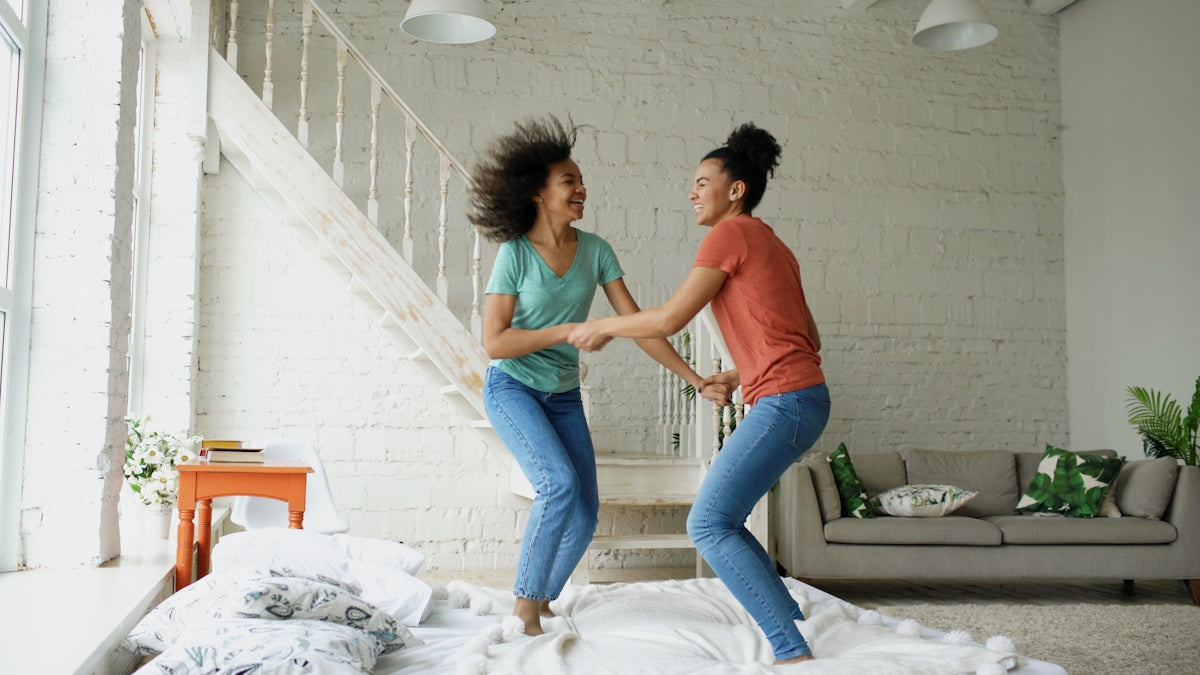 Two women jumping on a bed together
