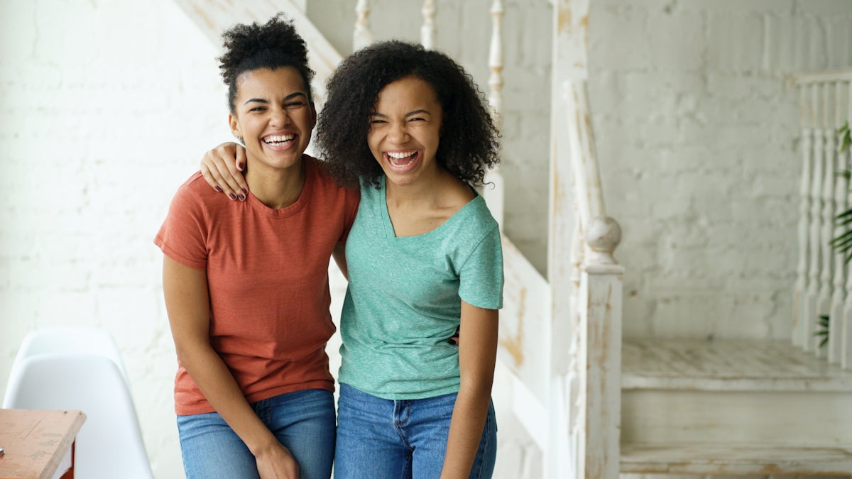 Two happy young women laughing together indoors