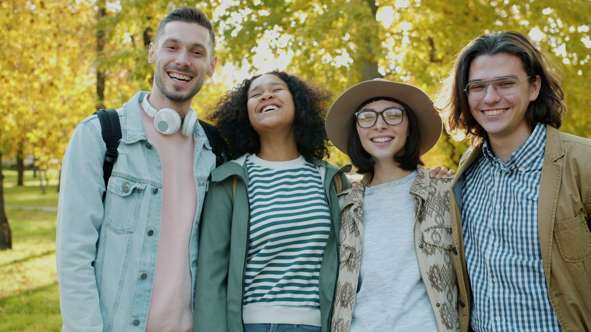Four smiling friends posing together outdoors in autumn.