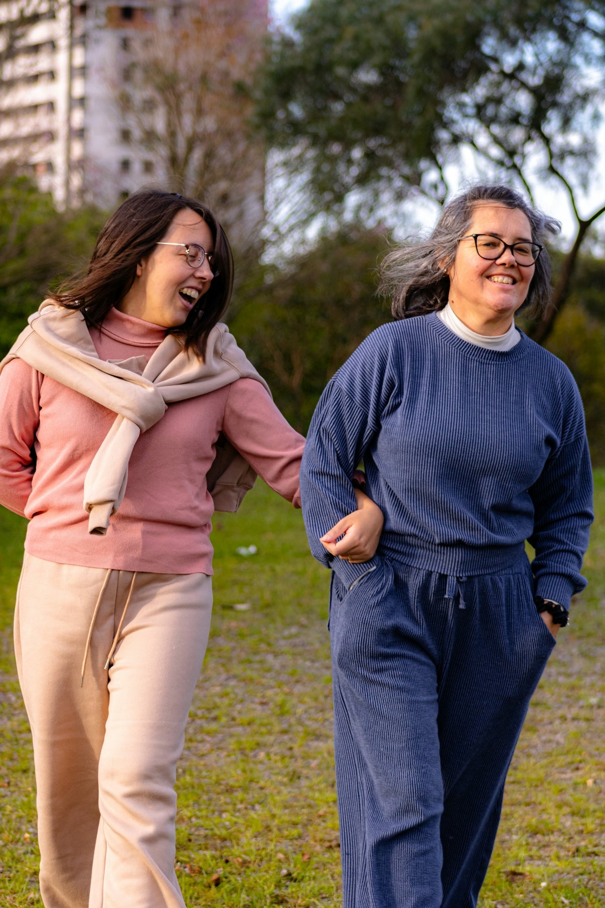 Two women laughing and walking in a park.