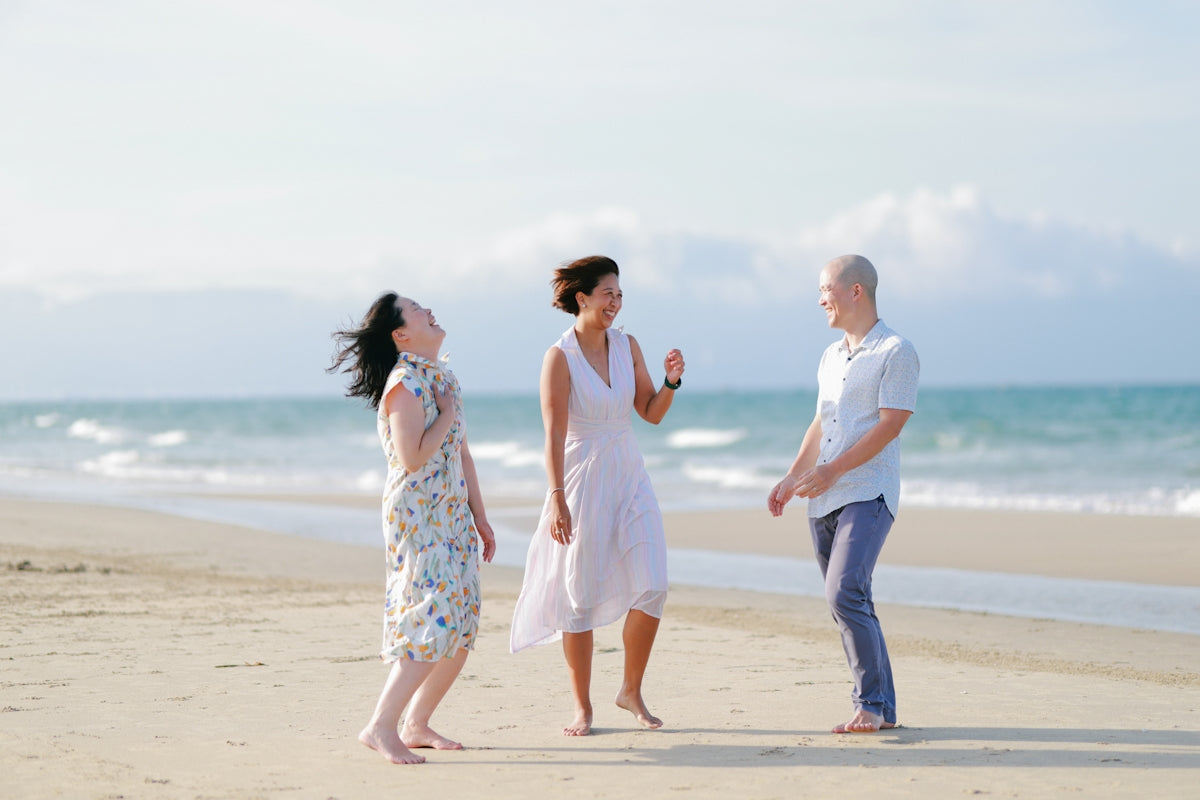 Three friends laughing on a sunny beach