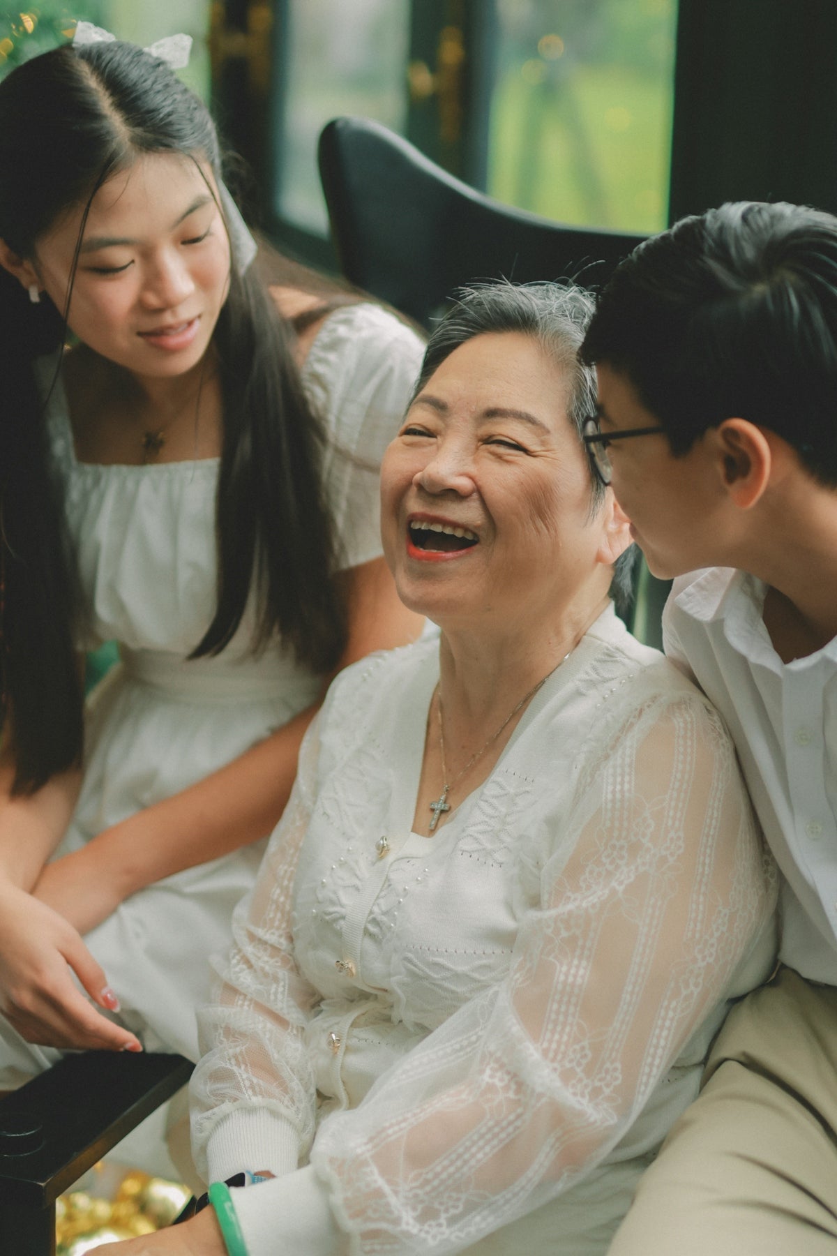 Grandmother laughing with her grandchildren, wearing white.