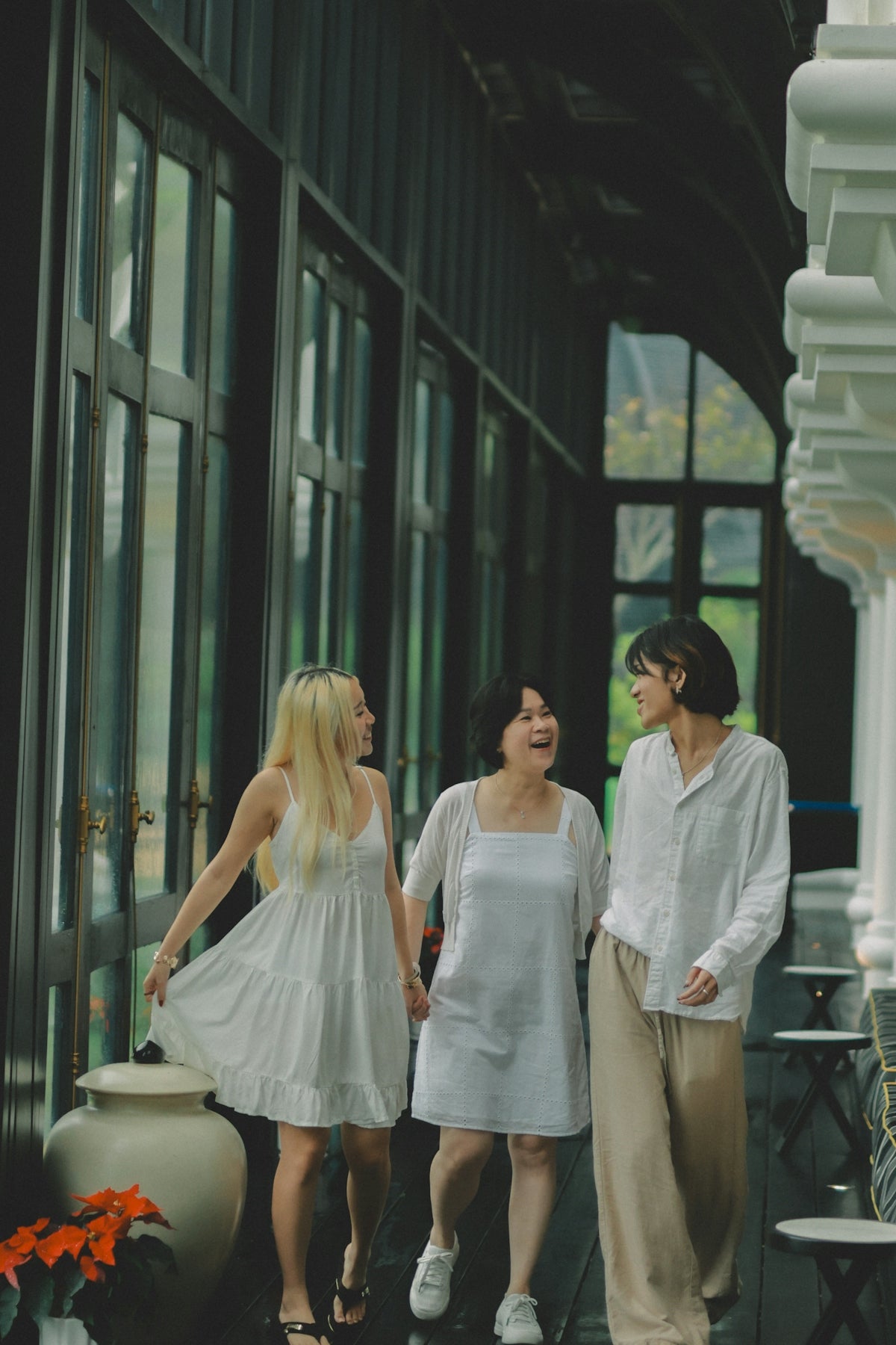 Three women in white walking together and smiling.