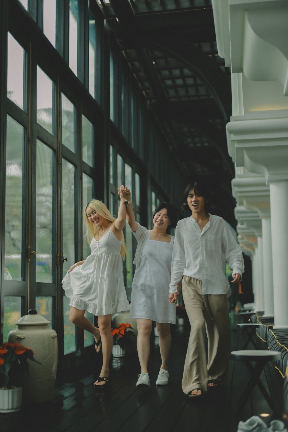 Three friends in white clothes walking together joyfully.