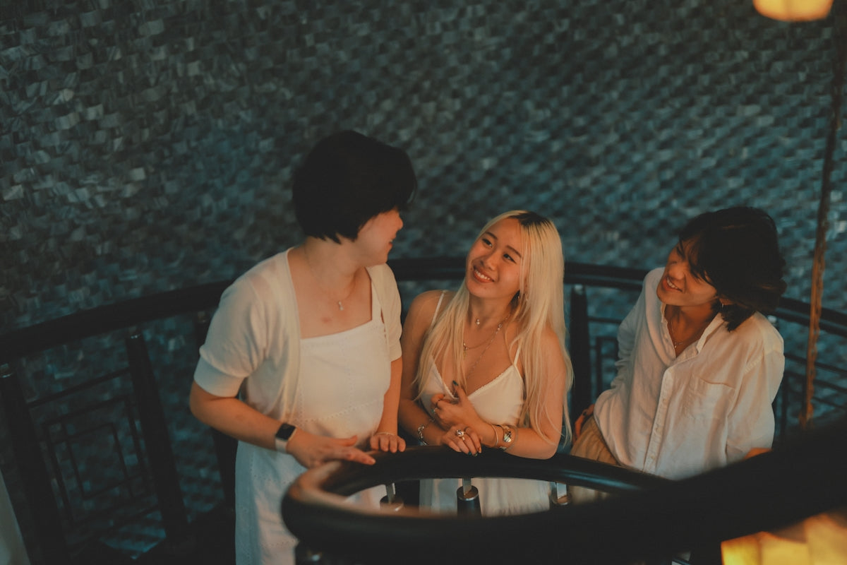 Three friends laughing together on a balcony.