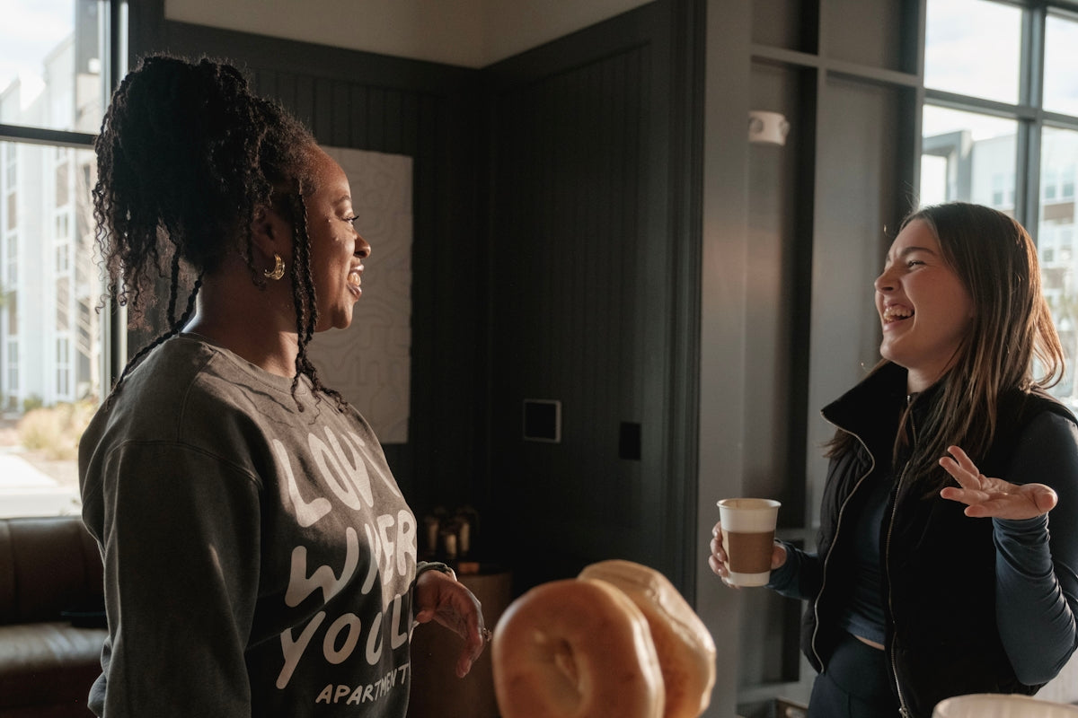 Two women talking and laughing indoors.