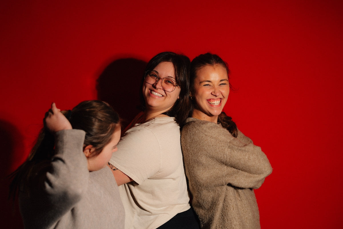 Three friends laughing against a red background