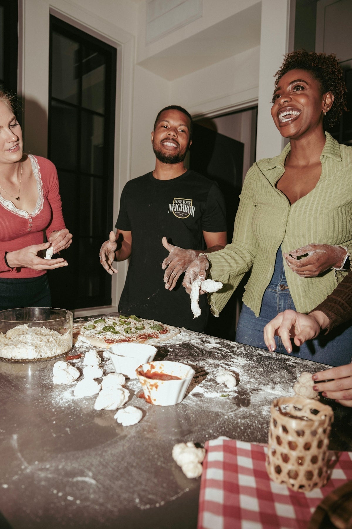 Friends making pizza together at a kitchen counter.