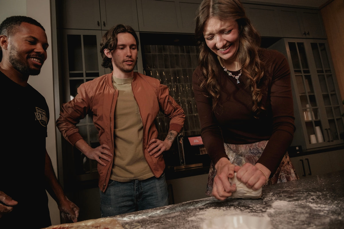 Three friends making dough together in a kitchen