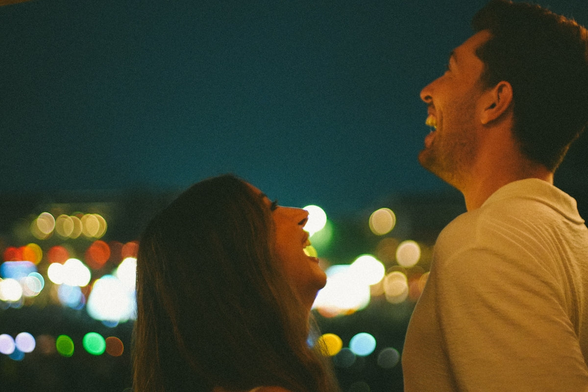 A couple laughing together at night with bokeh lights